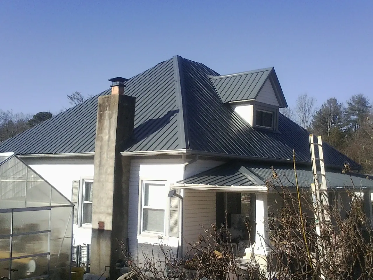 Dark blue standing seam metal roof on a white farmhouse with dormer — Slate & Tile Roof Repair by Roofing Brothers in Vincent