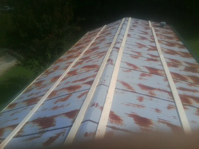 Rusted metal roof panels with new wood purlins before replacement in Vincent